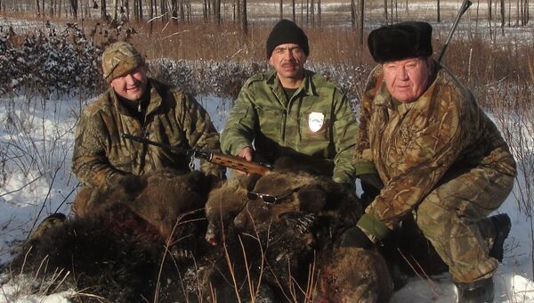 Человек похожий на Ивана Ряжских стоит с ружьем на фоне убитой медведицы с медвежатами