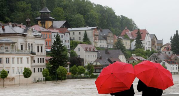 Люди смотрят на последствия наводнения, стоя под зонтами, Австрия