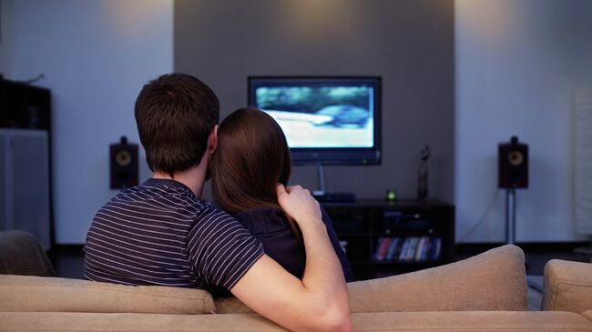 Девушка и молодой человек смотрят телевизор