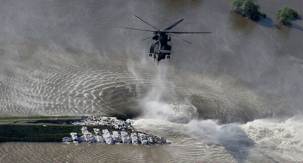 Вертолет сбрасывает мешки с песком на месте разрушенной дамбы в Германии