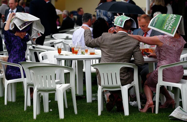 Люди прячутся от дождя во время Королевских скачек Royal Ascot