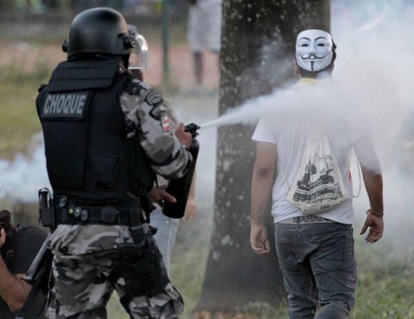 Полицейский применяет слезоточивый газ против демонстранта в Салвадоре