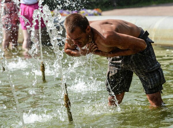 Мужчина умывается в фонтане Александровского садика в Санкт-Петербурге