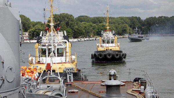 Буксиры следуют за эсминцем Настойчивый, помогая ему выйти из гавани Балтийска