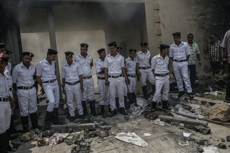 Полицейские в оцеплении у разгромленного здания штаб-квартиры политического движения Братья-мусульмане в Каире Полицейские в оцеплении у разгромленного здания штаб-квартиры политического движения Братья-мусульмане в Каире