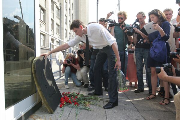 Участник пикета против реформы РАН возлагает цветы к символической надгробной плите у здания Государственной Думы в Москве