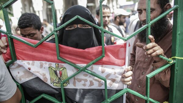 Женщина держит флаг Египта, на который кровью нанесены надписи