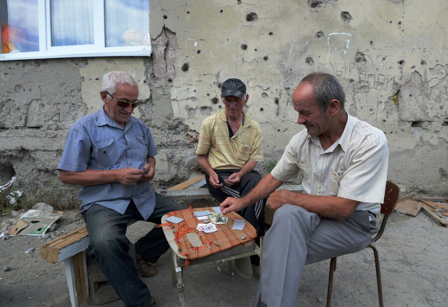 Мужчины играют в карты во дворе своего дома на одной из улиц в городе Цхинвал