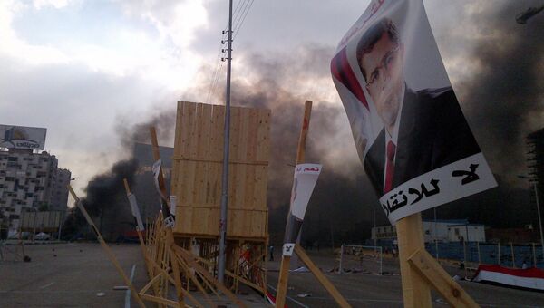 Плакат Мохаммеда Мурси на фоне дыма, где идет разгон лагеря исламистов