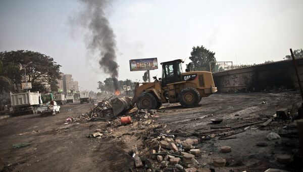 Трактор очищает улицу после столкновений в Каире