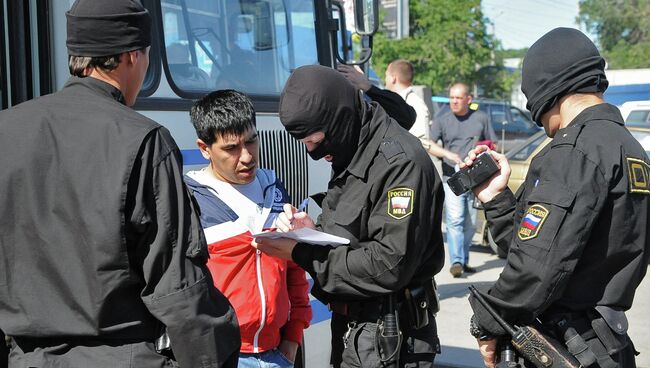 Сотрудник ОМОН регистрируют задержанного во время рейда на одном из рынков