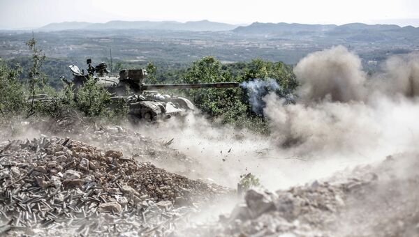 Танк правительственных войск ведет огонь по позициям боевиков во время боевых действий неподалеку от турецкой границы. Архивное фото