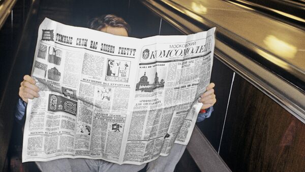 Пассажир московского метро читает газету, сидя на ступенях движущегося эскалатора на станции Фрунзенская.