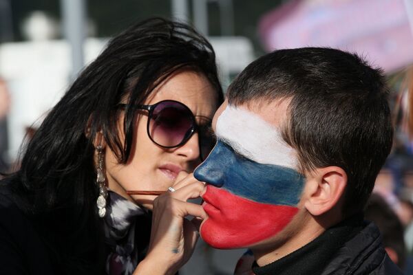 Девушка разрисовывает лицо молодому человеку перед КСК Фетисов-Арена во Владивостоке