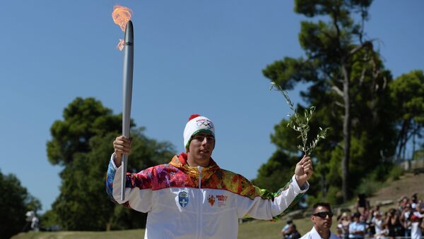 Первый факелоносец эстафеты огня XXII зимних Олимпийских игр 2014 года, греческий горнолыжник Яннис Антониу бежит с Олимпийским факелом и оливковой ветвью на полуострове Пелопоннес в Греции.