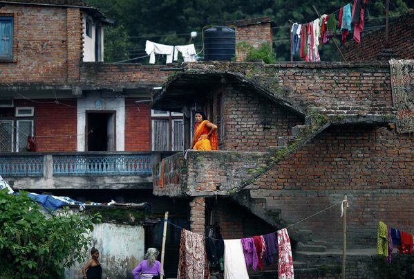 Женщина стоит на балконе дома у берега реки Багмати, протекающей через храм Пашупатинатх в Катманду
