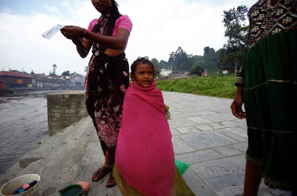 Девочка стоит в полотенце после купания в реке Багмати, протекающей через храм Пашупатинатх в Катманду