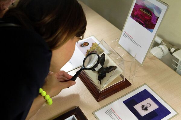 Девушка рассматривает экспонат на выставке микроминиатюр в Томском музее славянской мифологии