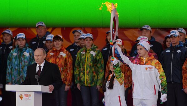 Президент РФ Владимир Путин (слева) на Красной площади во время старта эстафеты Олимпийского огня. Справа - фигуристы Лина Федорова и Максим Мирошкин.