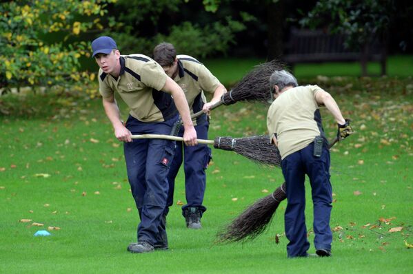 Дворники убирают листву с газона перед Букингемским дворцом