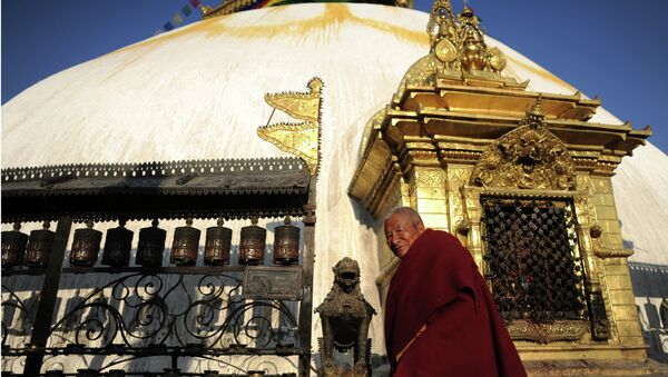 Буддийский монах у молельных колес и Ступы. Архивное фото.