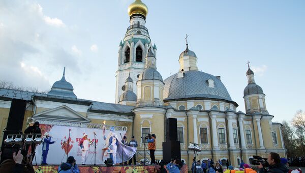 Дед Мороз на сцене у Софийского собора демонстрирует зрителям Олимпийский факел