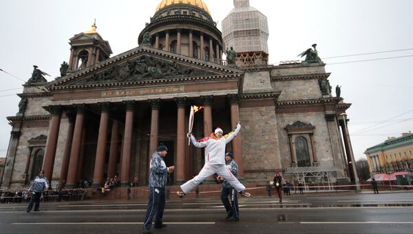 Факелоносец во время эстафеты Олимпийского огня около Исаакиевского собора в Санкт-Петербурге