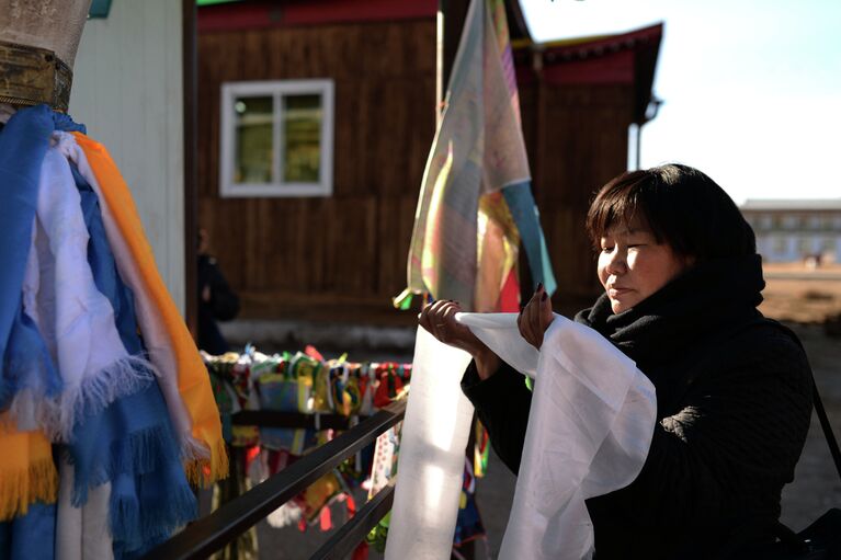 Верующая совершает обряд около одного из дуганов (храмов) при обходе Иволгинского дацана