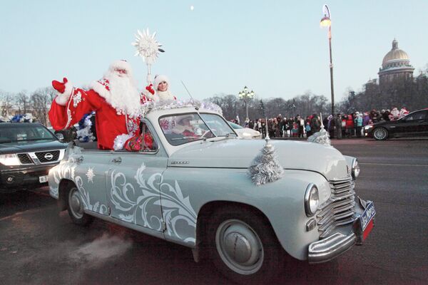 Дед Мороз на ретро-автомобиле приветствует жителей Санкт-Петербурга во время праздничного шествия на Сенатской площади
