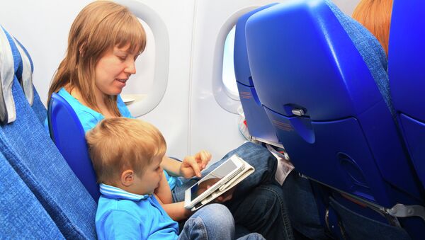 Мама с ребенком пользуются планшетом на борту самолета