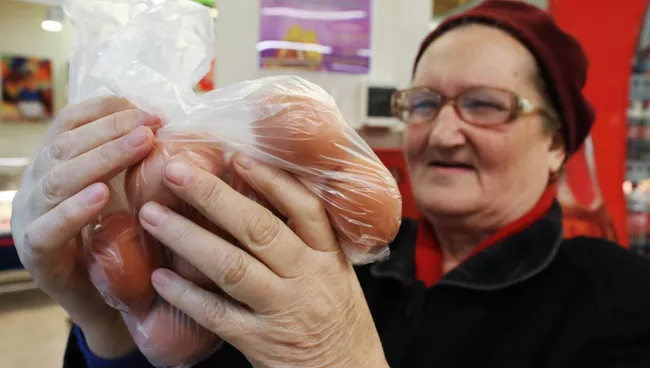 Покупательница выбирает куриные яйца в продуктовом магазине. Архивное фото