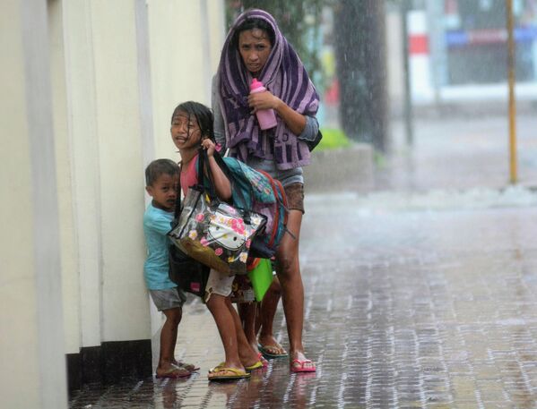 Мать с детьми прячутся от дождя во время тайфуна на Филиппинах