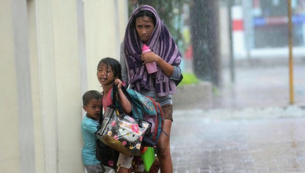 Мать с детьми прячутся от дождя во время тайфуна на Филиппинах. Архивное фото