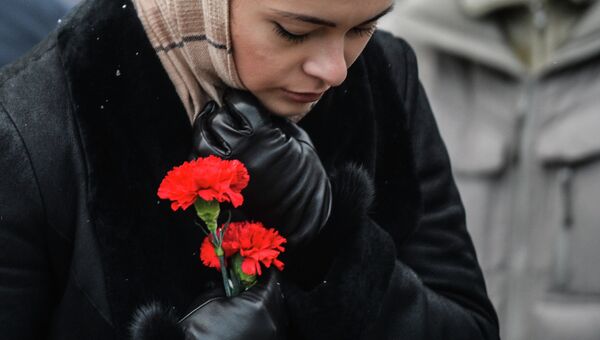 Женщина в международном аэропорту Казань несет цветы в память о погибших в авиакатастрофе самолета Boeing 737 авиакомпании Татарстан,