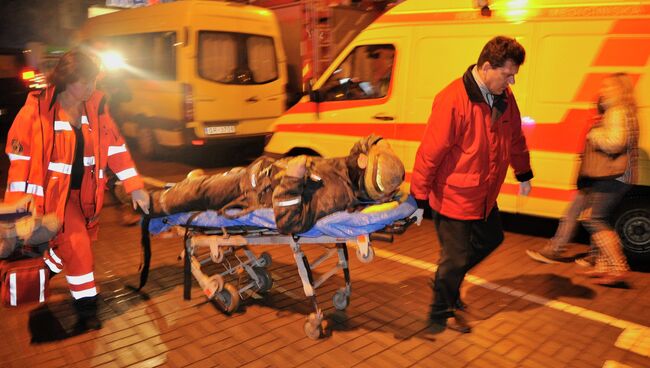 Медики скорой помощи везут носилки с сотрудником пожарно-спасательной службы, пострадавшим при разборе завалов от обрушения крыши в торговом центре Maxima