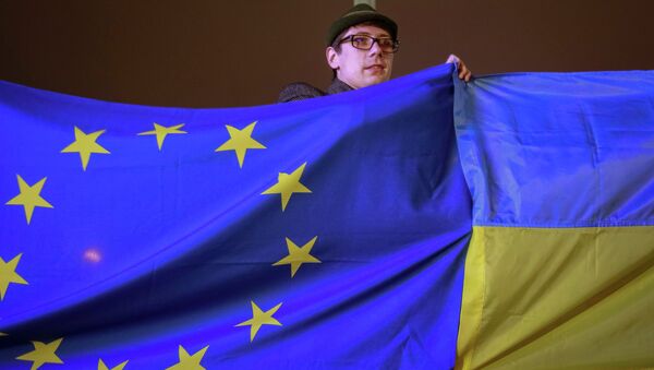 Протестующий держит украинский флаг и флаг Евросоюза во время митинга в поддержку евроинтеграции. Архивное фото