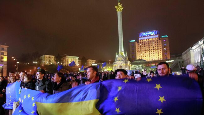 Протестующие держат украинские флаги и флаги Евросоюза во время митинга в поддержку евроинтеграции, Киев