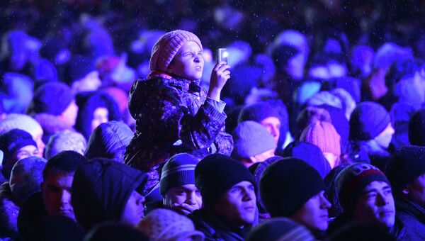 Девочка фотографирует на телефон салют во время торжественной церемонии зажжения чаши Олимпийского огня в Томске, событийное фото