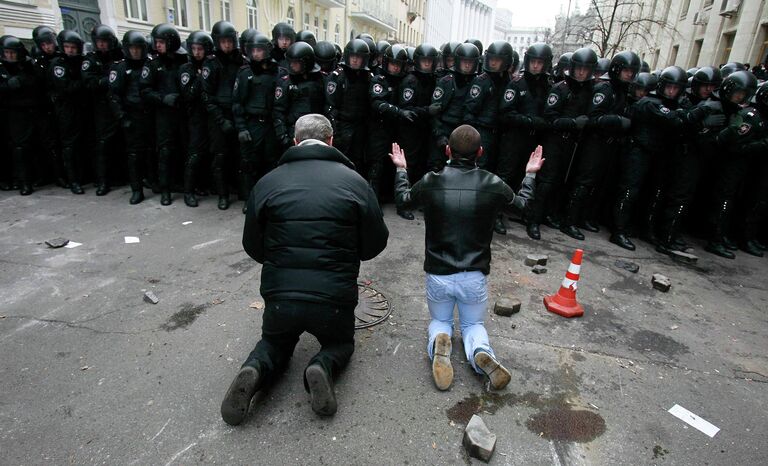 Люди стоят на коленях перед милицией во время митинга сторонников евроинтеграции в Киеве