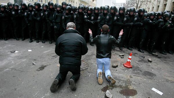 Люди стоят на коленях перед милицией во время митинга сторонников евроинтеграции в Киеве