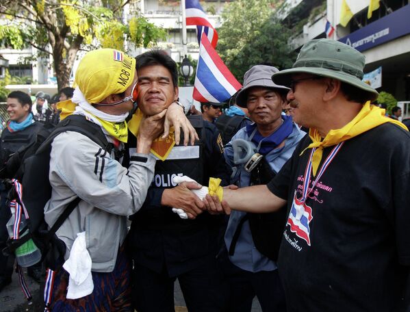 Протестант обнимается с полицейским во время перемирия после столкновений в Бангкоке