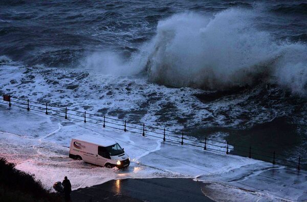 Фургон проезжает сквозь воду во время шторма на севере Англии
