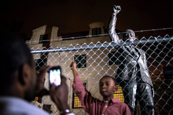 Дижон Андерсон Боуи фотографирует своего сына Китона перед статуей Нельсона Манделы у Южно-Африканского посольства в Вашингтоне