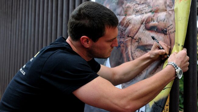 Человек пишет сообщение на плакате с Нельсоном Манделой на улице Вилакази в Соуэто, где бывший президент ЮАР проживал Человек пишет сообщение на плакате с Нельсоном Манделой на улице Вилакази в Соуэто, где бывший президент ЮАР проживал