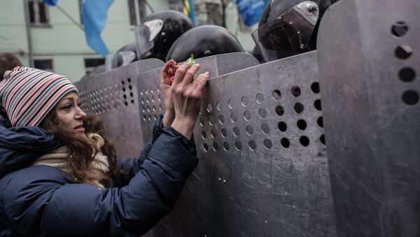Девушка предлагает конфеты милиционерам, стоящим в оцеплении на улице Грушевского в Киеве