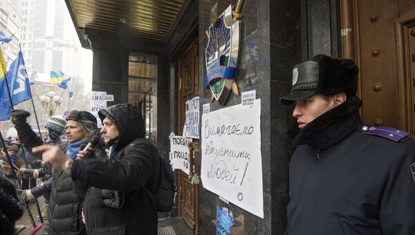 Сотрудник правоохранительных органов (справа) и сторонники евроинтеграции Украины у здания генеральной прокуратуры в Киеве. 9 декабря 2013