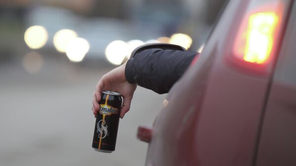 Водитель пьет энергетический напиток за рулем автомобиля