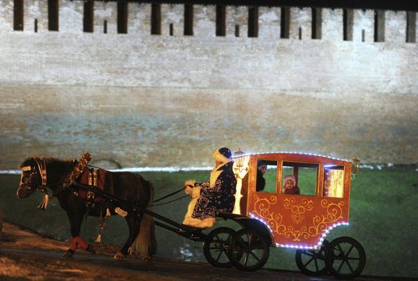 Дети катаются в карете, запряженной лошадью, у стен Кремля в Великом Новгороде