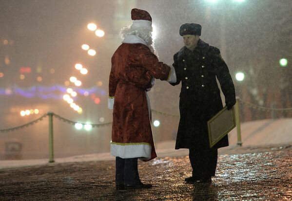 Сотрудник правоохранительных органов встречает водителя в костюме Деда Мороза, который привез в Кремль главную Новогоднюю елку страны
