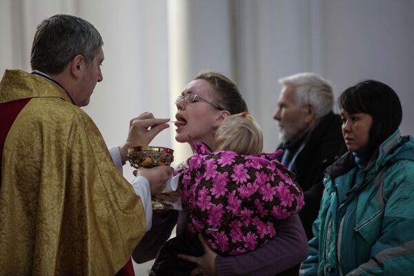 Викарий католического прихода Пресвятой Богородицы во Владивостоке отец Даниил раздает святое причастие во время Рождественской службы.